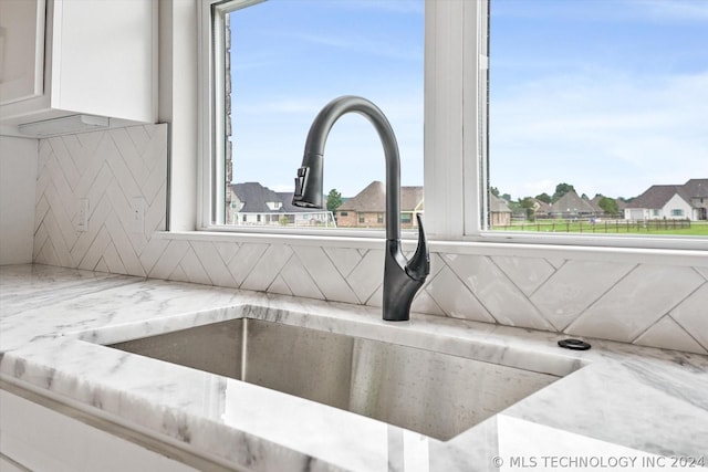 room details with light stone counters, white cabinets, and sink