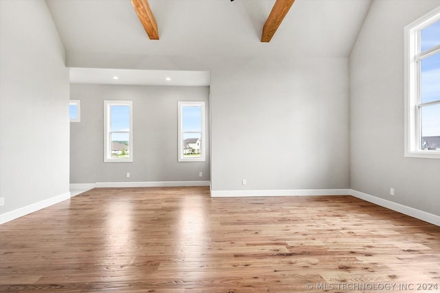 unfurnished room featuring vaulted ceiling with beams and light hardwood / wood-style flooring