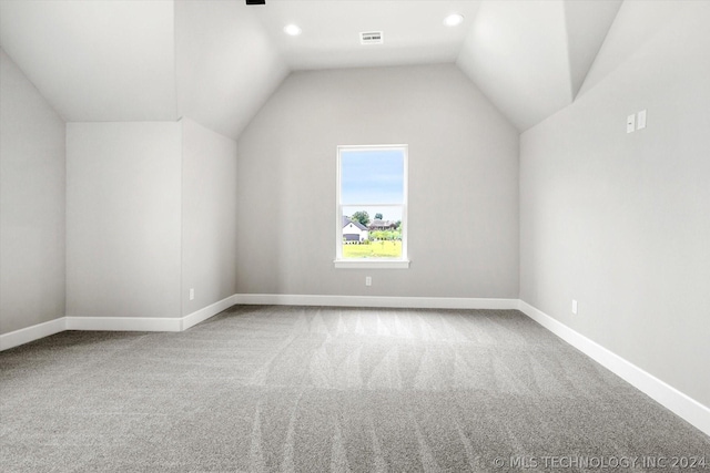 additional living space with carpet floors, lofted ceiling, visible vents, and baseboards