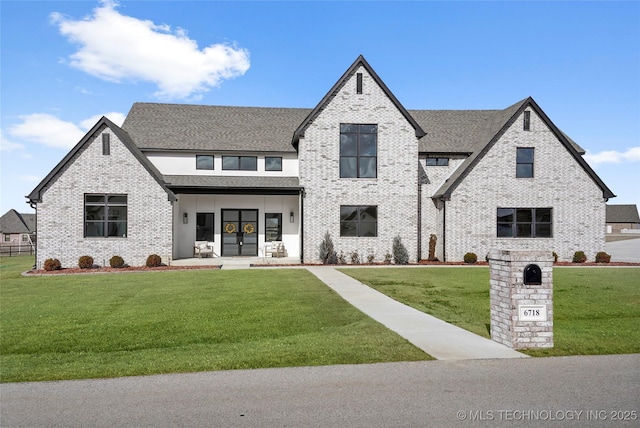 view of front of house featuring a front yard, french doors, brick siding, and roof with shingles