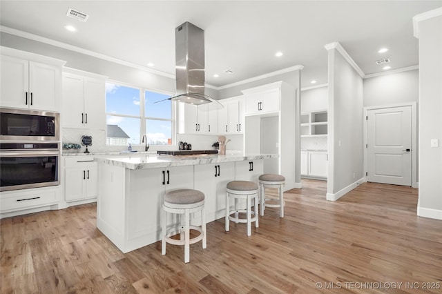 kitchen with stainless steel appliances, white cabinetry, a center island, tasteful backsplash, and island exhaust hood