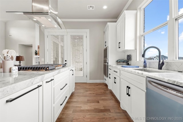 kitchen featuring visible vents, appliances with stainless steel finishes, white cabinetry, a sink, and light stone countertops