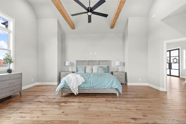 bedroom with lofted ceiling with beams, baseboards, and wood finished floors