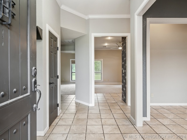 entrance foyer with ceiling fan, light colored carpet, and ornamental molding