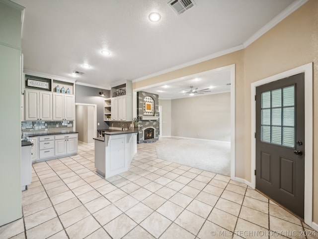 kitchen with white cabinets, a kitchen bar, kitchen peninsula, ceiling fan, and crown molding