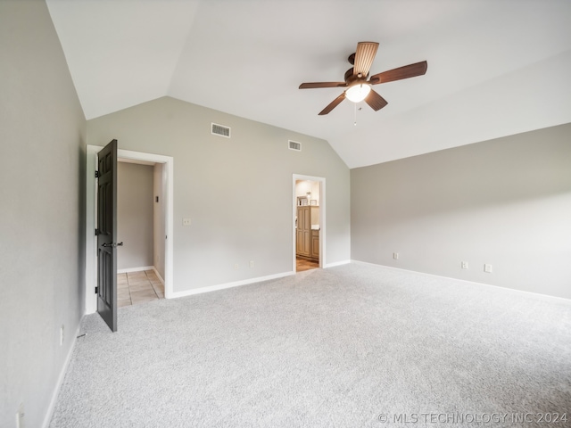 unfurnished bedroom with ceiling fan, light colored carpet, ensuite bath, and vaulted ceiling