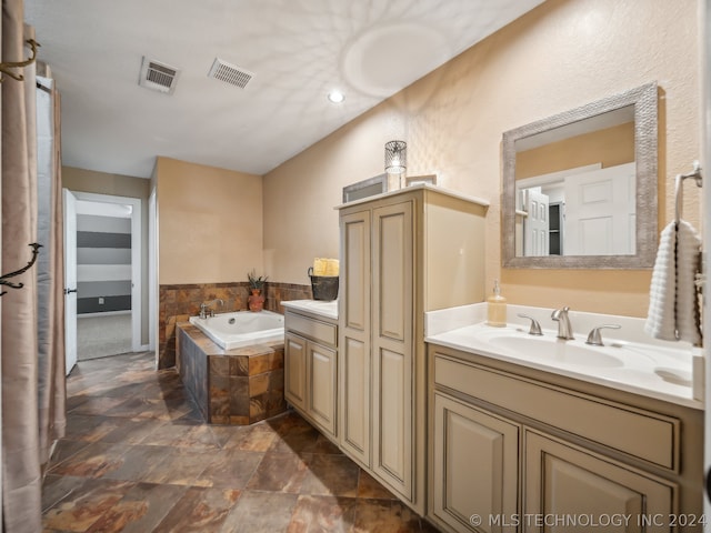 bathroom featuring vanity and a relaxing tiled tub