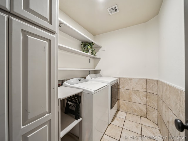 washroom with tile walls, washer and dryer, and light tile patterned flooring