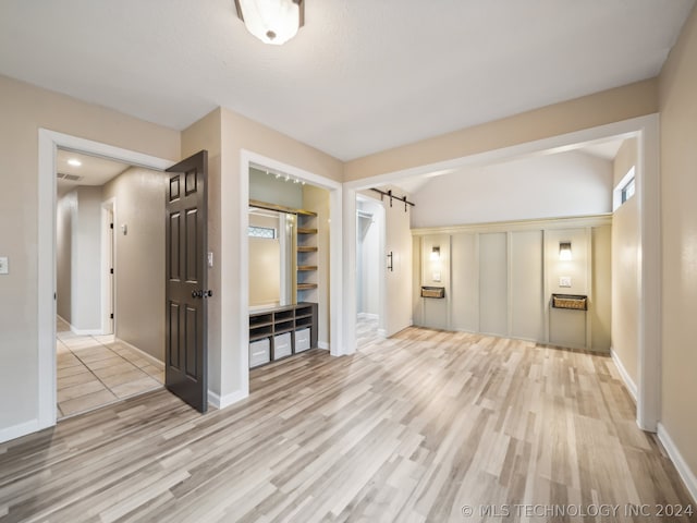 interior space with a barn door, built in features, a textured ceiling, and light hardwood / wood-style flooring