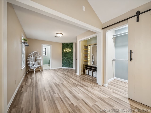 entrance foyer featuring vaulted ceiling, light hardwood / wood-style floors, and a barn door