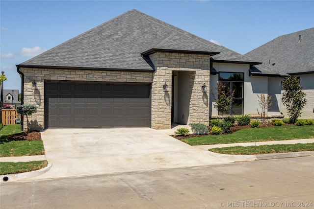 french provincial home with a garage and a front lawn