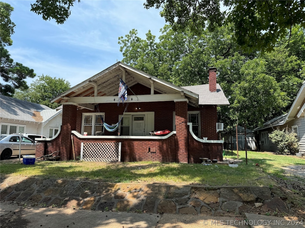 view of front of house with a front yard, a chimney, and brick siding