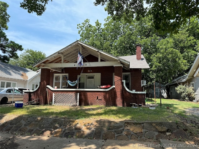 view of front of house with a front yard, a chimney, and brick siding