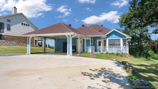 rear view of property featuring covered porch, a carport, and a lawn