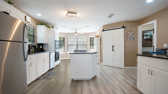 kitchen with sink, a kitchen island, appliances with stainless steel finishes, and light hardwood / wood-style flooring