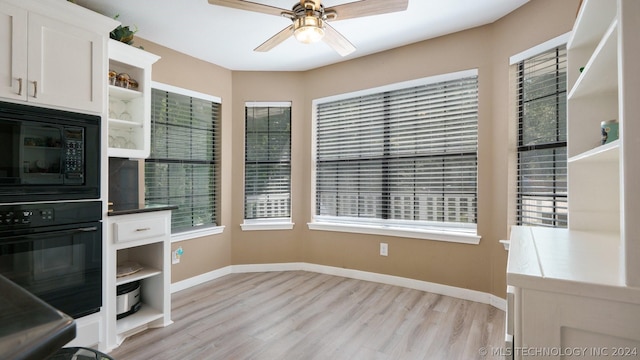 interior space with built in microwave, white cabinets, oven, ceiling fan, and light hardwood / wood-style floors