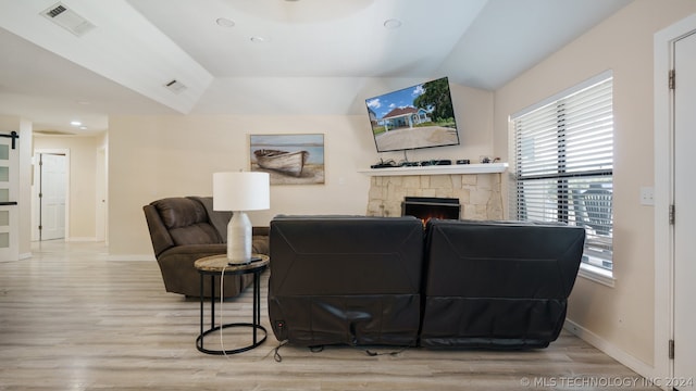 living room with light hardwood / wood-style floors and a stone fireplace