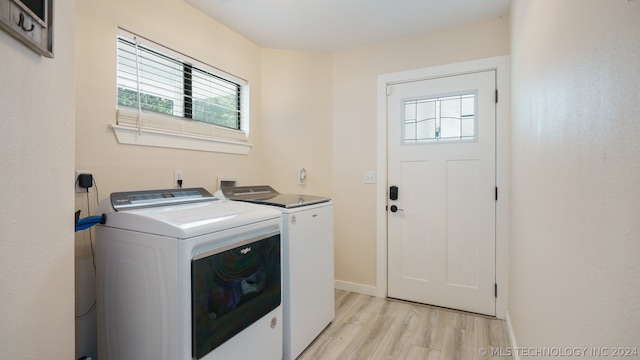 clothes washing area with washing machine and dryer and light wood-type flooring