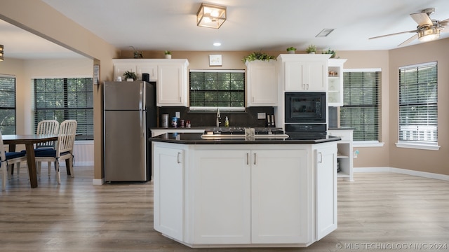 kitchen with decorative backsplash, light hardwood / wood-style flooring, black appliances, and white cabinets