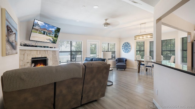 living room with ceiling fan, a fireplace, vaulted ceiling, and light hardwood / wood-style flooring