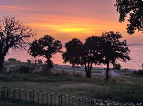 yard at dusk featuring a water view