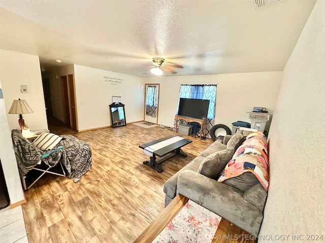 living room with light wood-type flooring, ceiling fan, and a textured ceiling