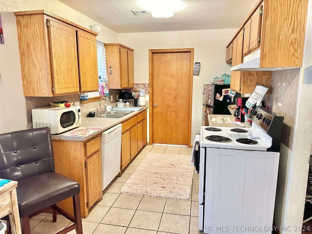 kitchen featuring light tile patterned floors, white appliances, sink, and a textured ceiling