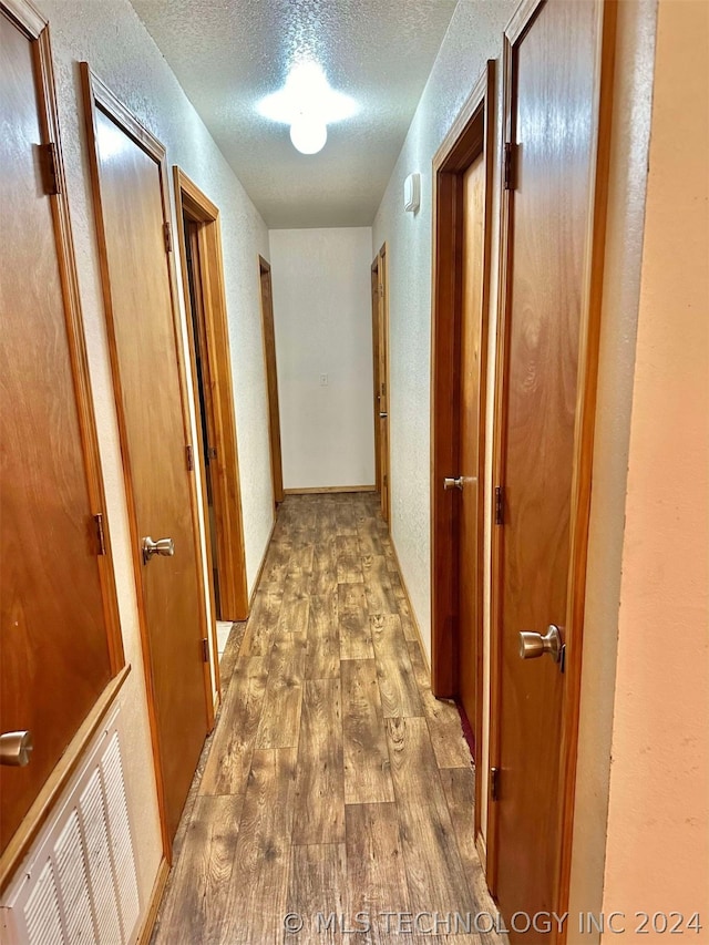 corridor featuring a textured ceiling and wood-type flooring