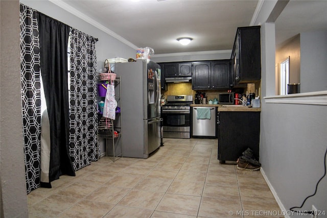 kitchen with appliances with stainless steel finishes, dark brown cabinets, backsplash, light tile patterned floors, and crown molding