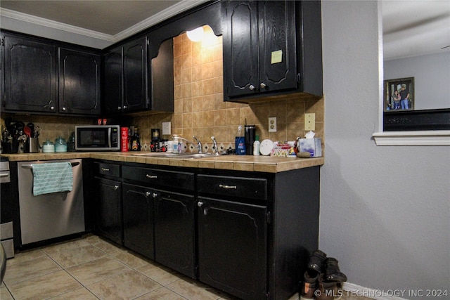 kitchen with light tile patterned flooring, crown molding, appliances with stainless steel finishes, decorative backsplash, and sink