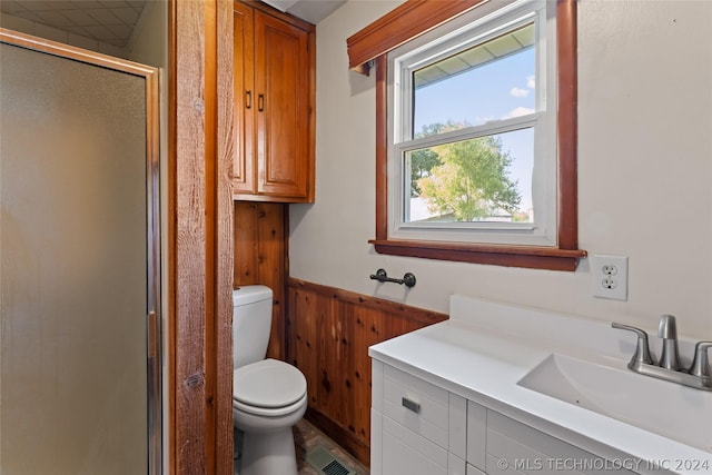 bathroom with toilet, vanity, an enclosed shower, and wooden walls