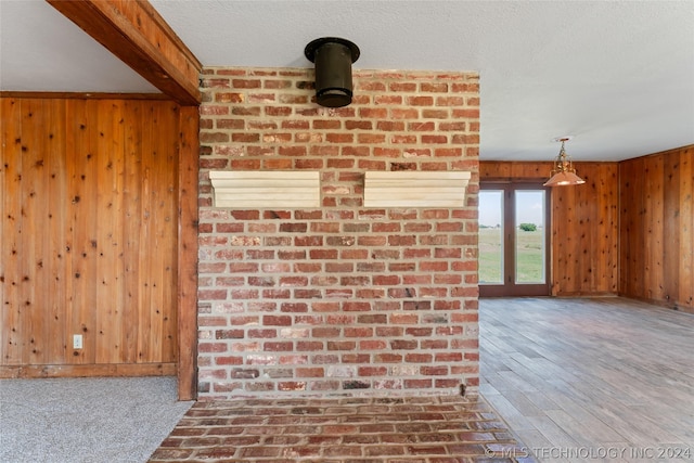 interior space featuring a textured ceiling, wood walls, and carpet flooring