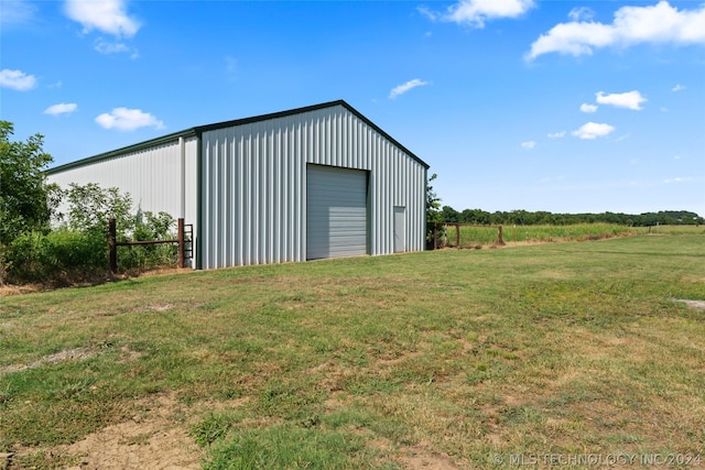 garage featuring a rural view and a lawn