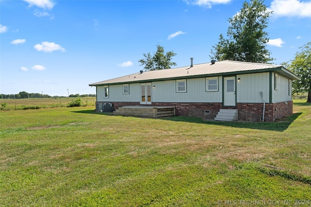 back of property featuring french doors and a lawn