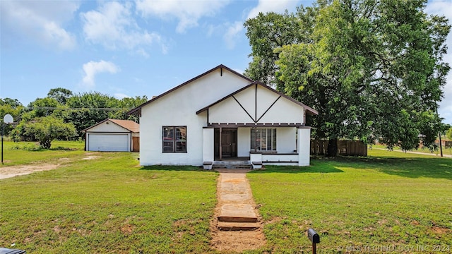 view of front of property with a front lawn, a garage, an outbuilding, and covered porch