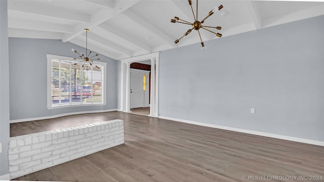 spare room with hardwood / wood-style floors, lofted ceiling with beams, and a notable chandelier