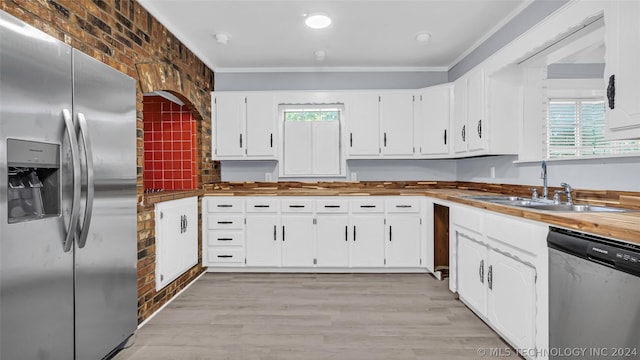 kitchen with brick wall, white cabinets, appliances with stainless steel finishes, and sink