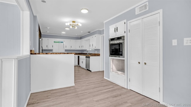 kitchen with an inviting chandelier, light hardwood / wood-style floors, stainless steel appliances, ornamental molding, and white cabinets