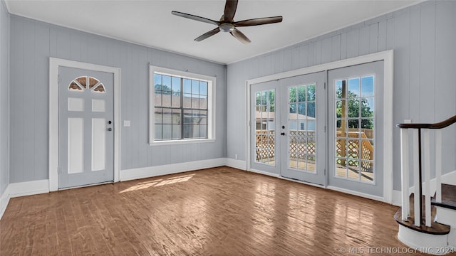 doorway with ceiling fan, hardwood / wood-style floors, wood walls, and french doors