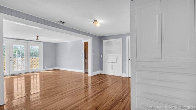 unfurnished living room with hardwood / wood-style flooring and built in features