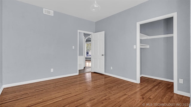 unfurnished bedroom featuring a closet and hardwood / wood-style floors