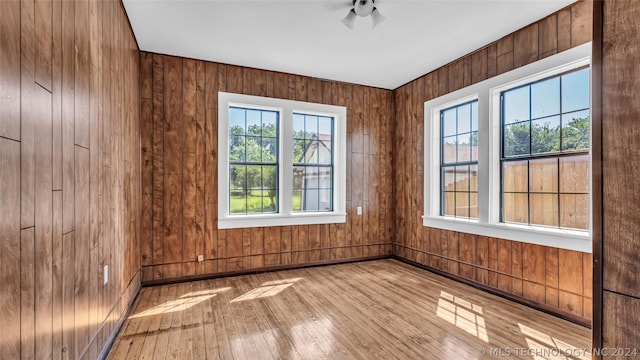 unfurnished room featuring light hardwood / wood-style flooring and wooden walls