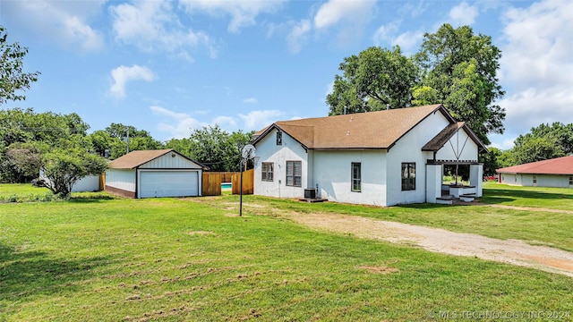 exterior space with central AC unit, a garage, an outbuilding, and a yard