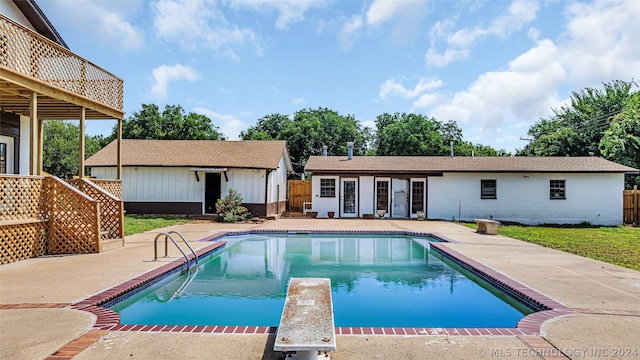 view of pool with a diving board, a patio area, and an outdoor structure