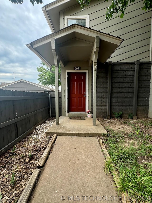 property entrance with brick siding and fence