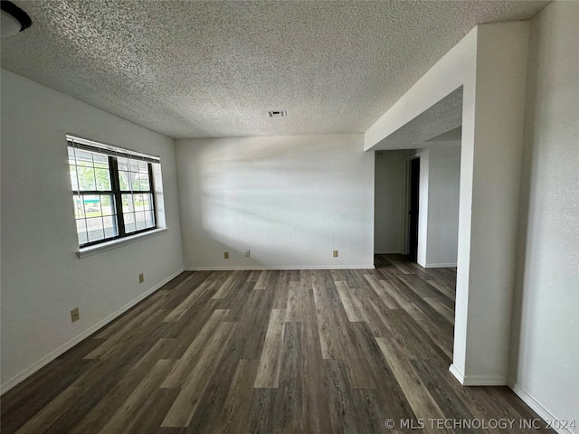 spare room with a textured ceiling and dark hardwood / wood-style flooring