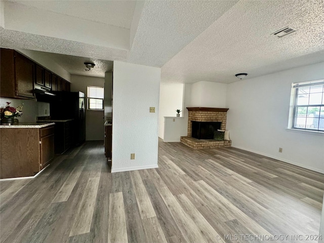 unfurnished living room featuring a textured ceiling, a healthy amount of sunlight, light hardwood / wood-style floors, and a fireplace