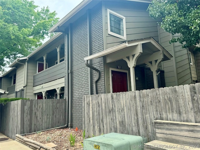 view of front of house featuring brick siding and fence