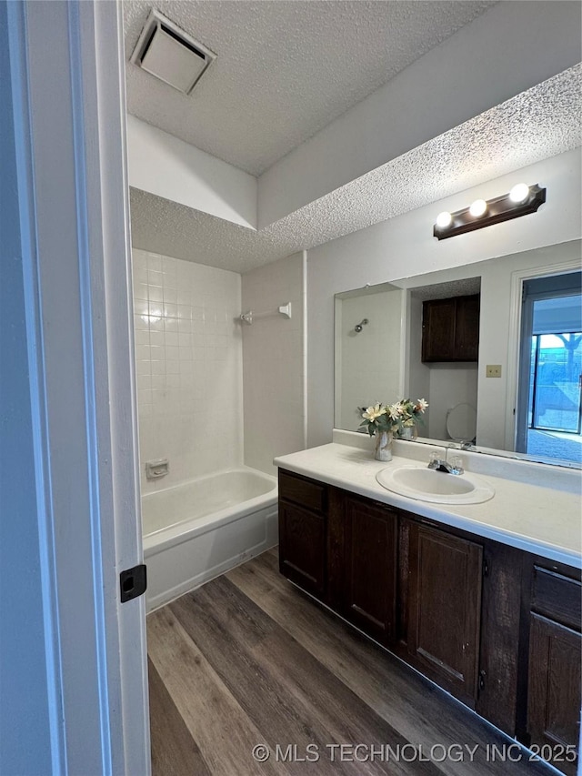 bathroom featuring visible vents, shower / bathing tub combination, a textured ceiling, vanity, and wood finished floors