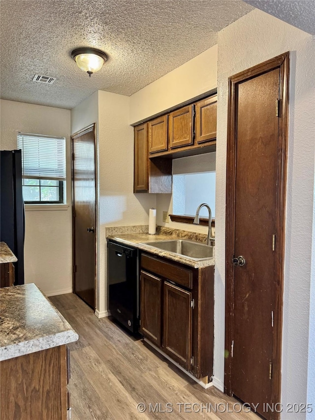9031 S Delaware Ave Unit 703, Tulsa, OK 74137 - kitchen featuring a textured ceiling, a sink, black appliances, light wood-style flooring, and visible vents